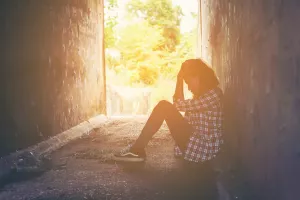 sunny day alley way woman lady female girl sitting down against wall upset with depression confusion side profile silhouette glowing sun outside