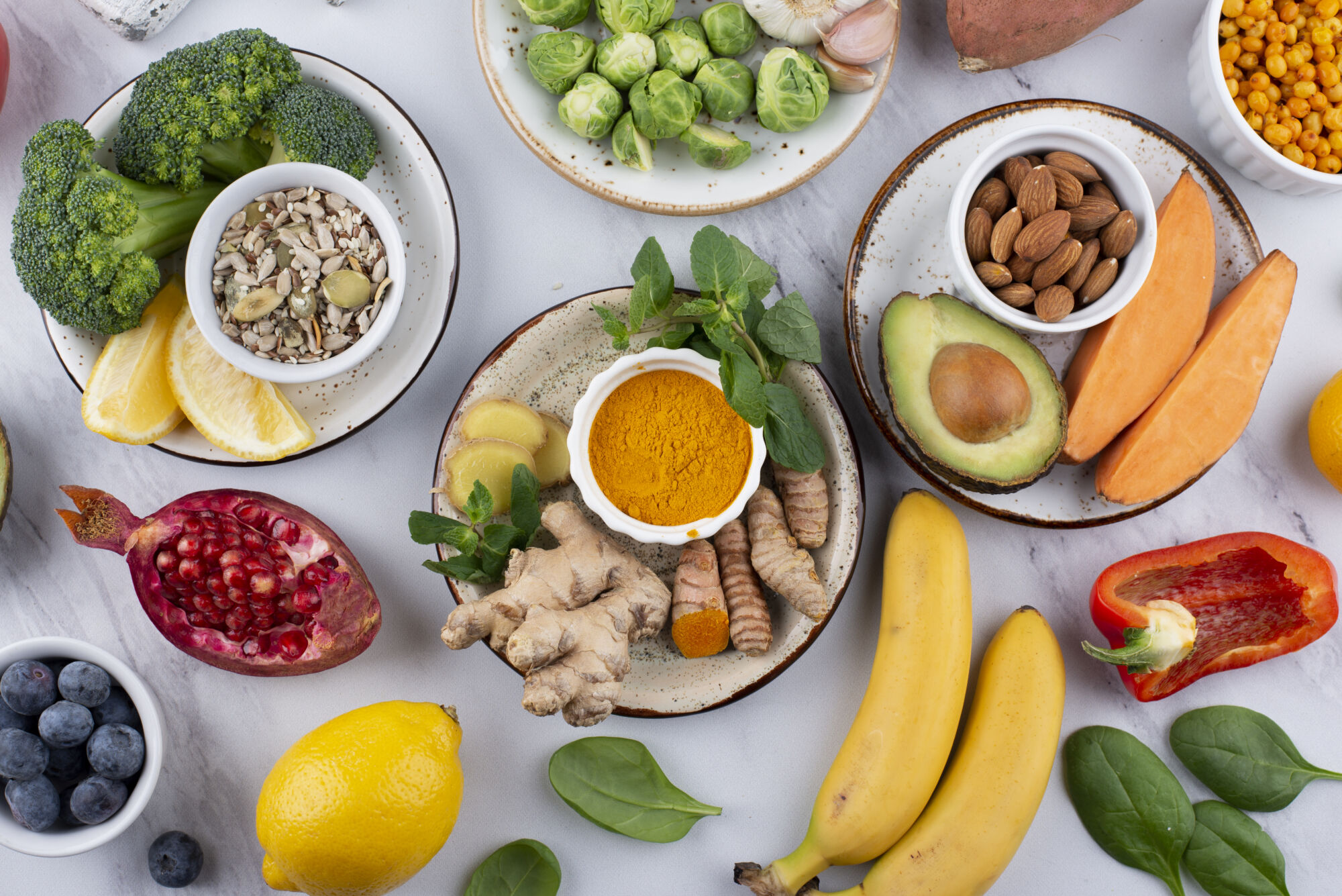 naturopathic doctor help food allergies selection in bowls with vegetables, fruits, nuts, brussels sprouts, brocolli, avocado, banana, sweet potatoe, ginger, pomegranate, peppers, almonds, corn, lemon, tumeric, mint, spinach, blueberry, garlic, sunflower seeds, oranges, citrus